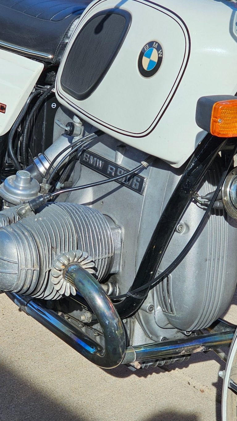 Yellow motorcycle with chrome details parked on a concrete surface by the water.